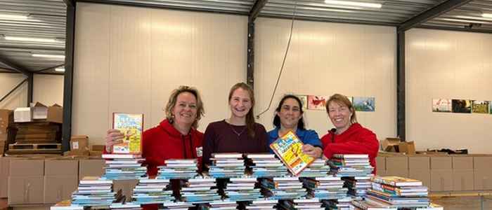 Rosa and Joy help hand out children's books at the Food Bank